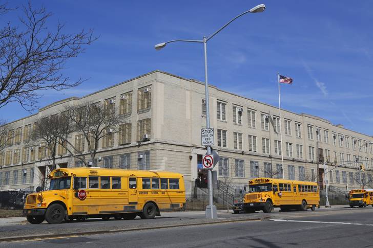 School buses in the front of a public school in Brooklyn.